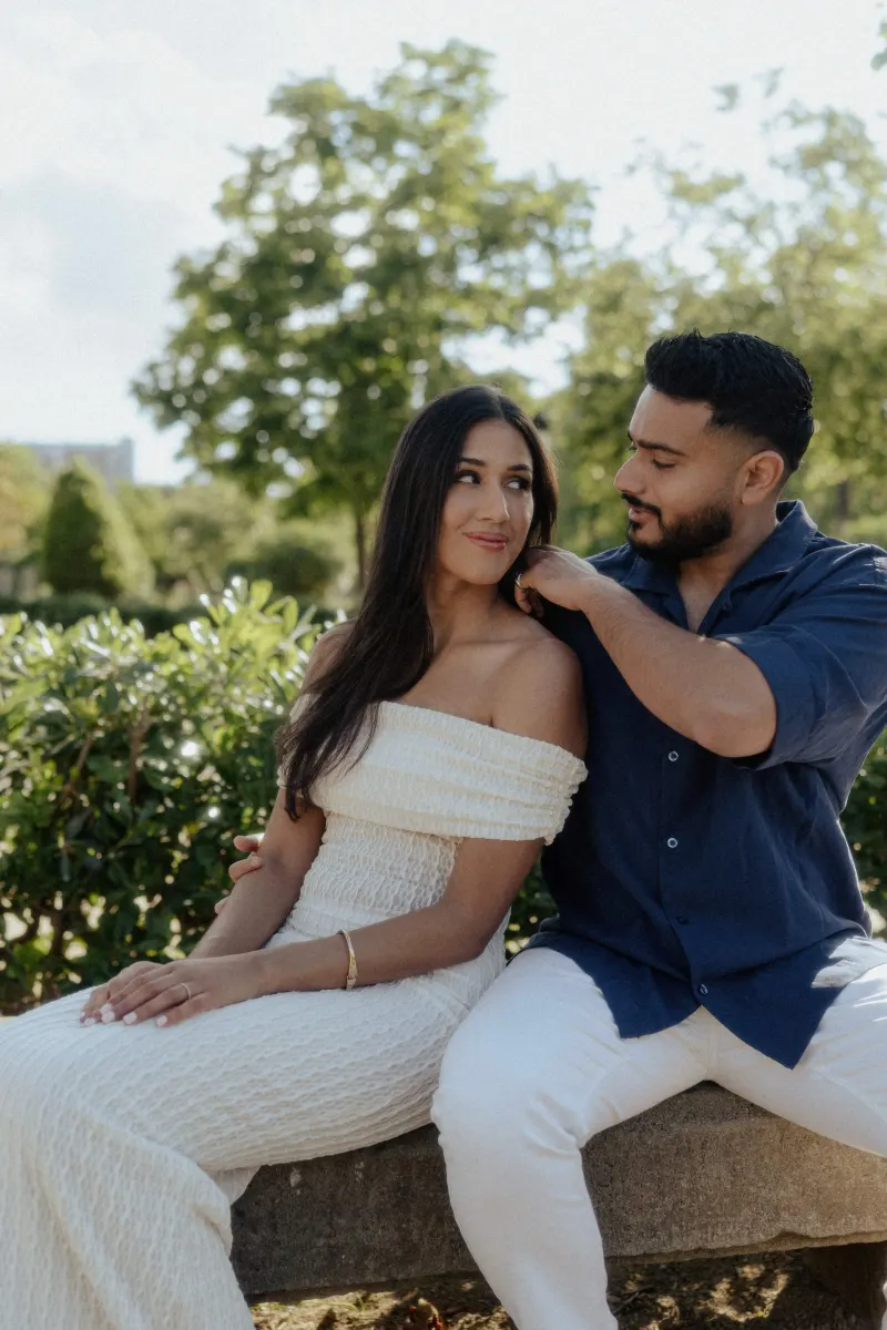 Couple sharing a playful, affectionate moment on a garden bench during a couples & engagements photoshoot outdoors.