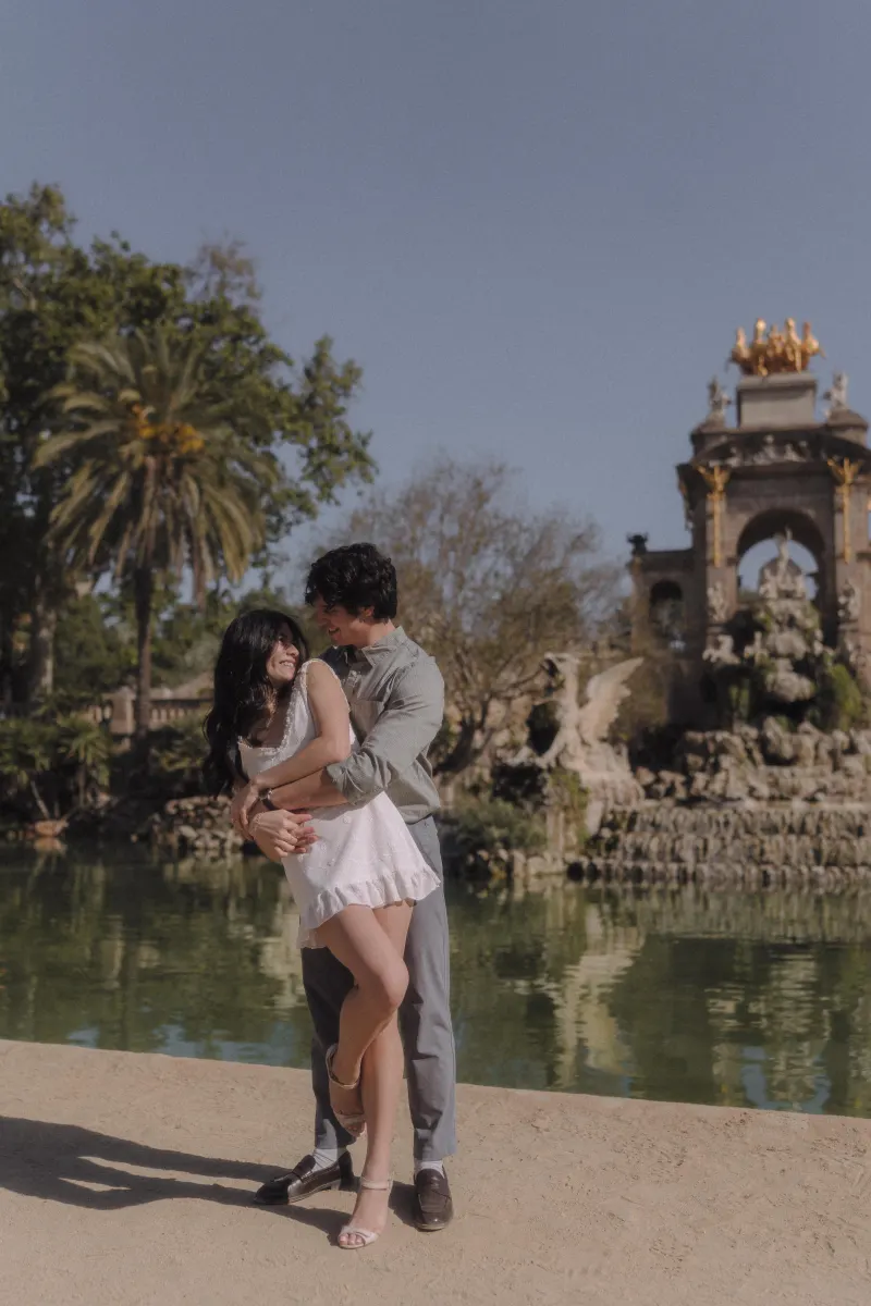 Couple sharing a playful embrace by the fountain at Parc de la Ciutadella during a couples & engagements photoshoot.