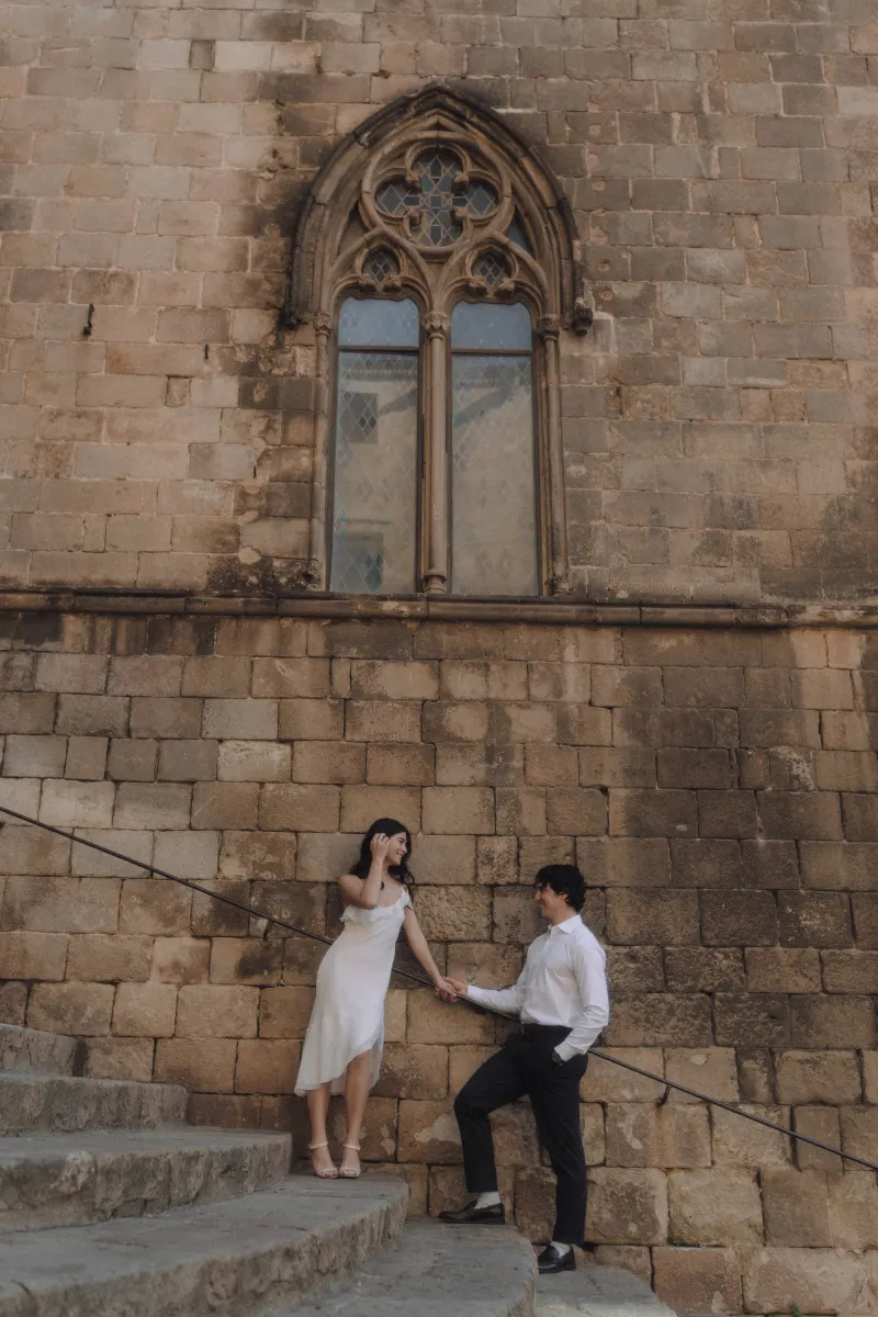 Couple sharing a playful moment on historic stone steps, holding hands during a couples & engagements photoshoot.