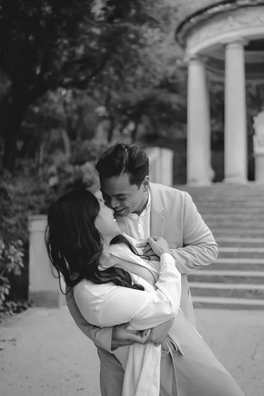 Couple sharing a playful, romantic moment near stone steps during a couples & engagements photoshoot in the park.