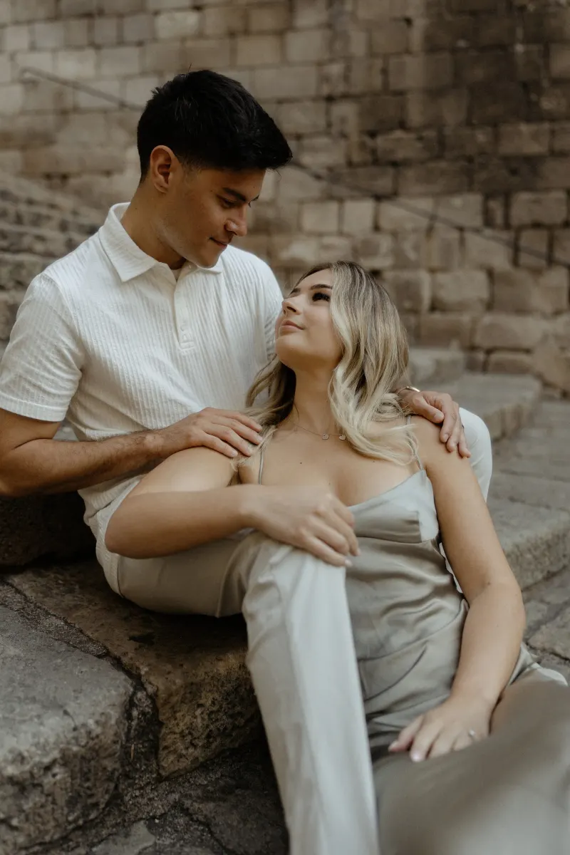 Couple sharing a quiet, affectionate gaze while sitting together on stone steps during a Vacation Portraits session in Barcel