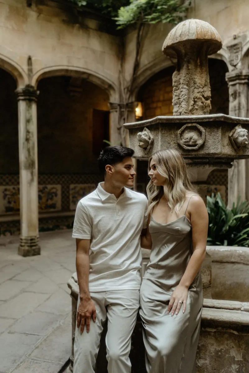 Couple sharing a quiet, affectionate moment by a stone fountain in Barcelona during a Vacation Portraits session.
