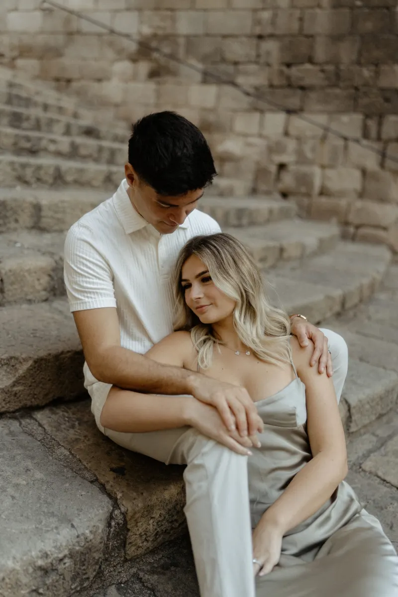 Couple sharing a quiet, affectionate moment on stone steps in Barcelona during a Vacation Portraits photoshoot.
