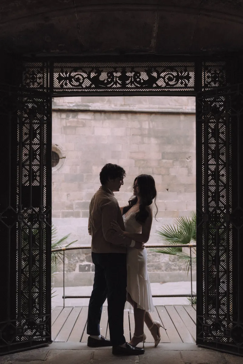 Couple sharing a quiet embrace in a historic archway, capturing a romantic moment during an engagement photoshoot.