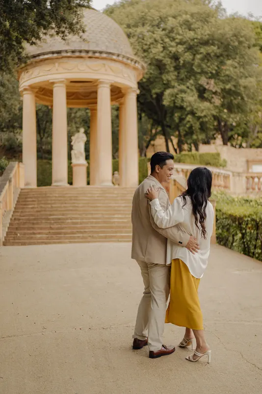 Couple sharing a quiet, joyful moment together near a classical pavilion during a couples & engagements photoshoot.