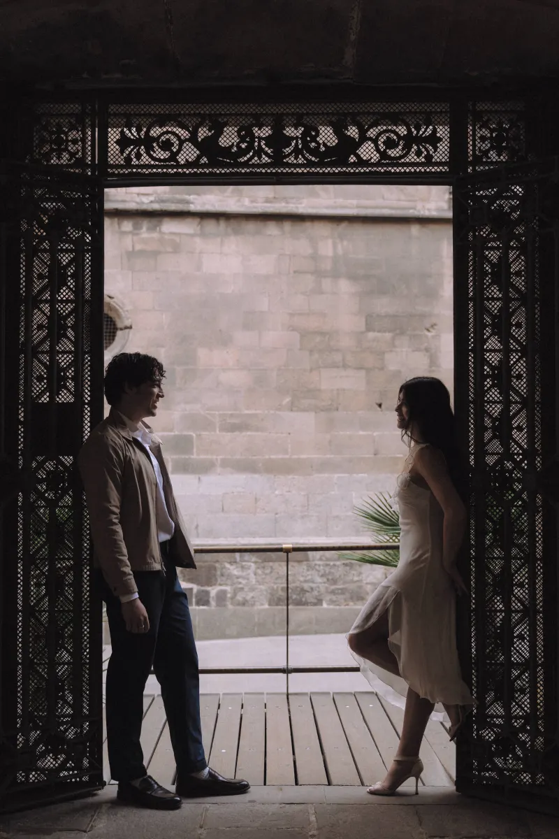 Couple sharing a quiet, playful moment in a historic archway during a couples & engagements photoshoot.