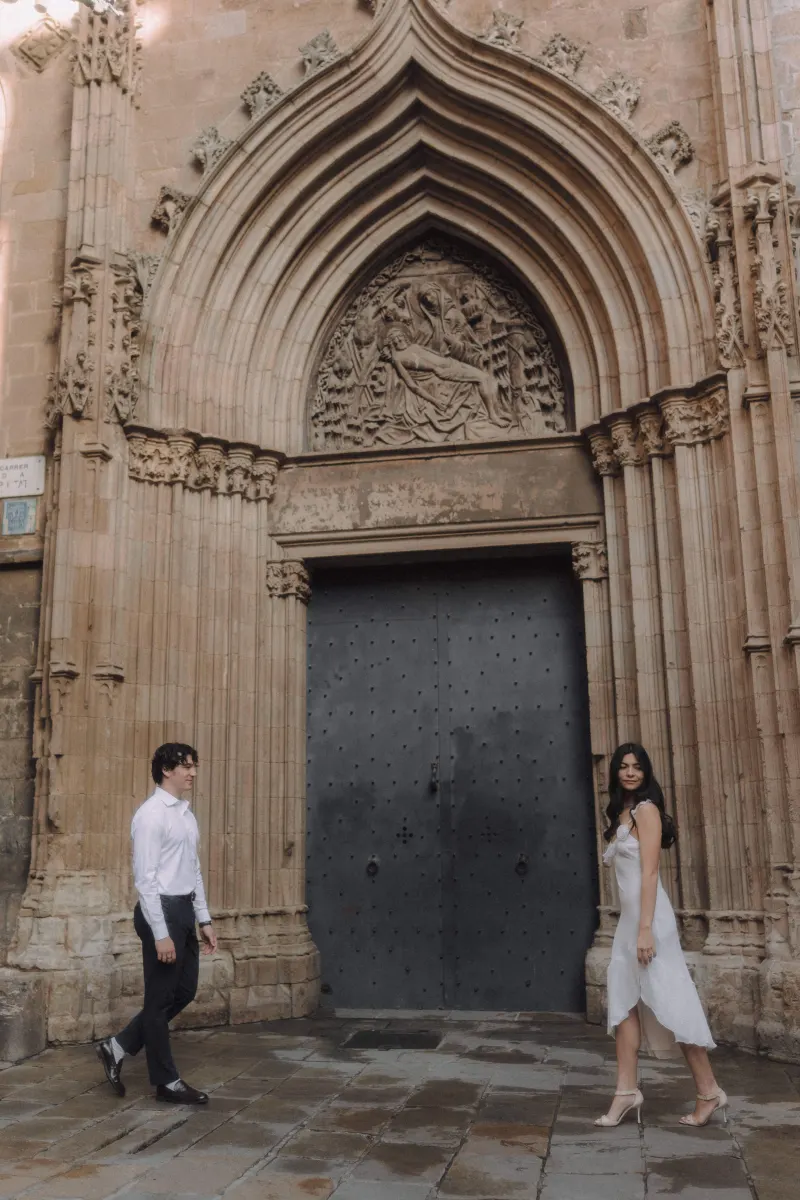 Couple sharing a quiet, romantic moment in front of a grand cathedral door during their engagement photoshoot.