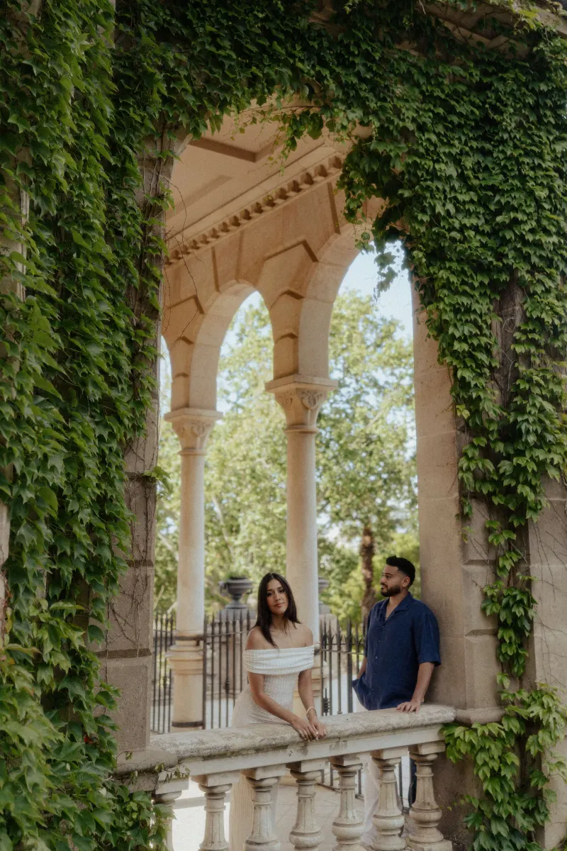 Couple sharing a quiet, romantic moment on a vine-covered stone balcony during a couples & engagements photoshoot in Barcelon