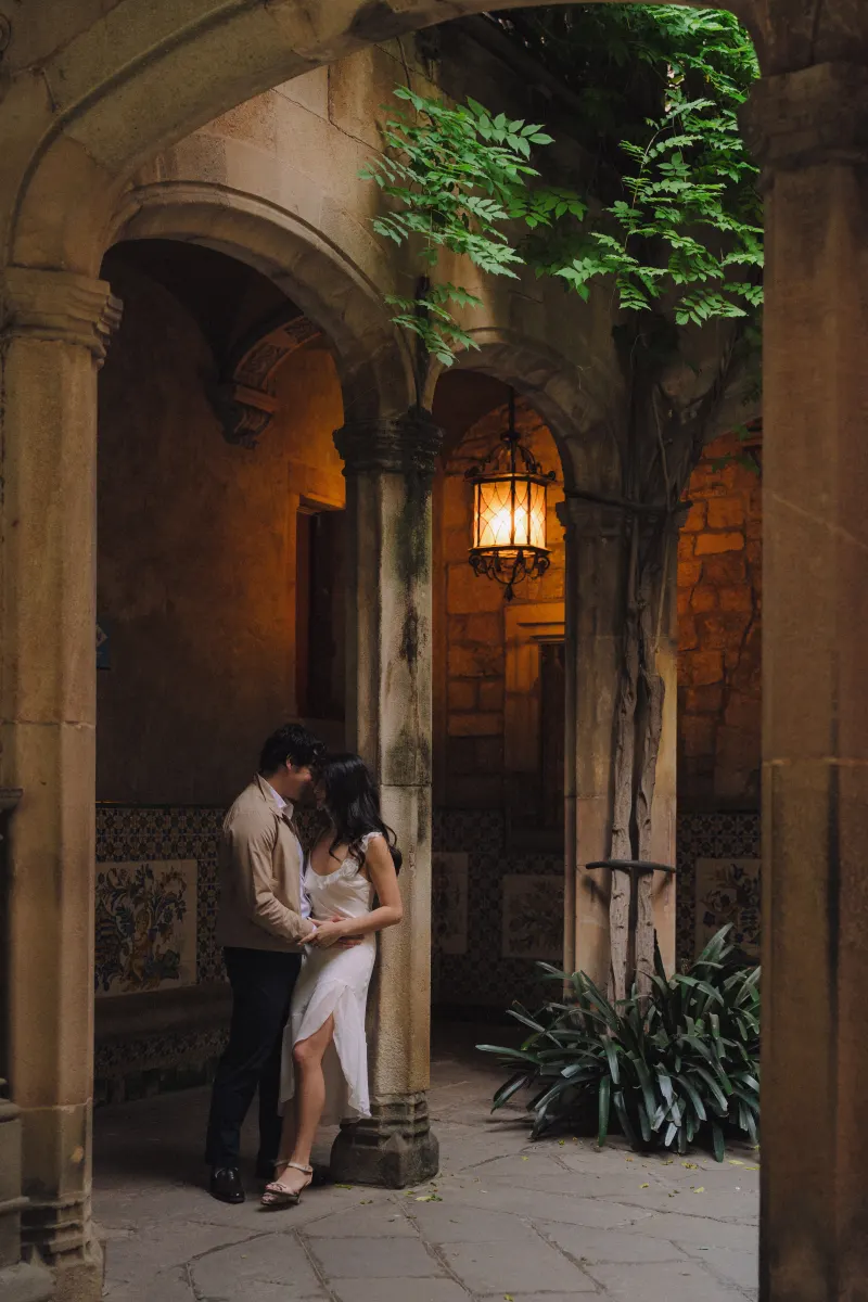 Couple sharing a quiet, romantic moment under stone arches during a couples & engagements photoshoot in a historic courtyard.