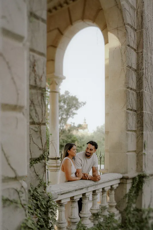 Couple sharing a relaxed, intimate moment on a vine-covered balcony during their engagement photoshoot in Parc de la Ciutadel