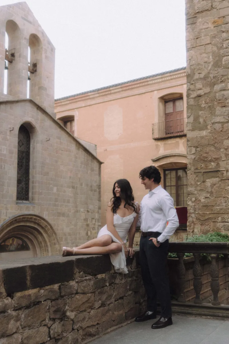 Couple sharing a relaxed, joyful moment in a historic courtyard during a couples & engagements photoshoot.