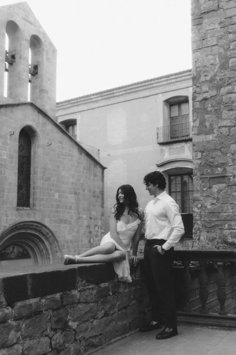 Couple sharing a relaxed moment on a stone terrace, smiling at each other during a couples & engagements photoshoot.