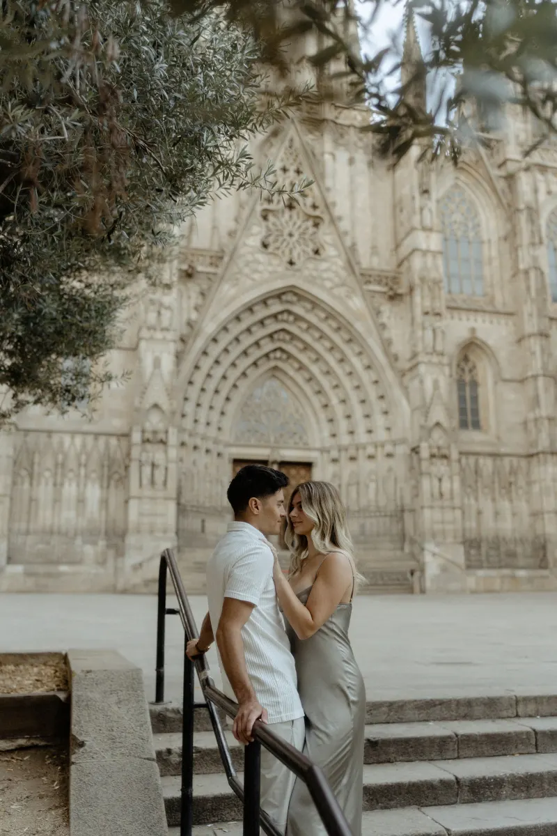 Couple sharing a romantic moment on cathedral steps in Barcelona during a Vacation Portraits photoshoot.