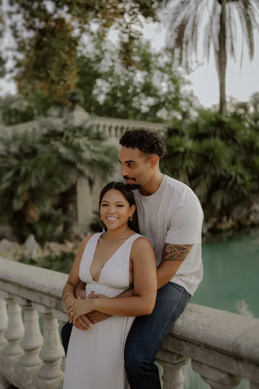 Couple sharing a sweet embrace by the water at Parc de la Ciutadella during a relaxed engagement photoshoot.