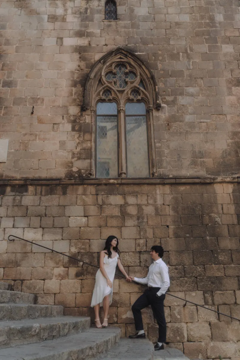 Couple sharing a sweet moment on historic stone steps, holding hands during a couples & engagements photoshoot.