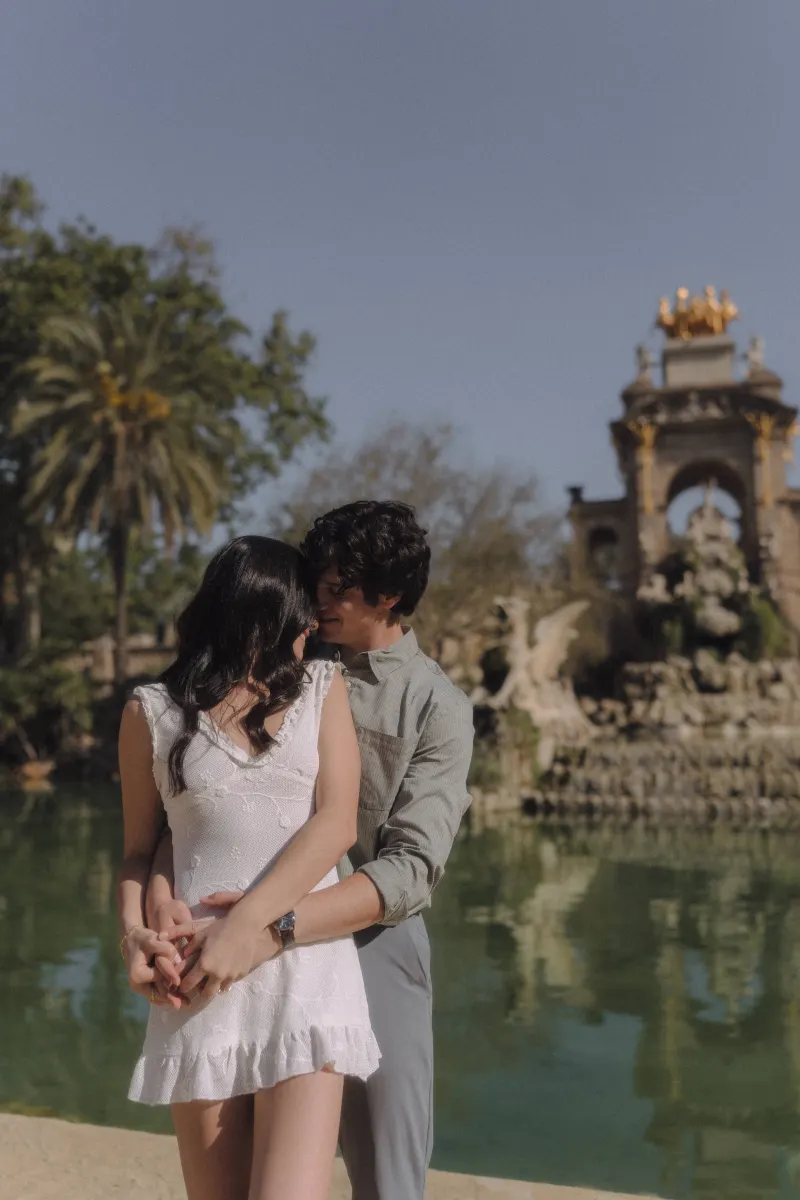 Couple sharing a tender embrace by the fountain at Parc de la Ciutadella during an engagement photoshoot.
