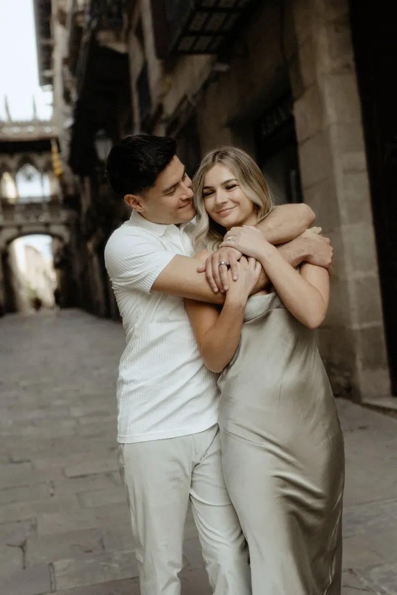Couple sharing a warm embrace on a quiet street in Barcelona during their Vacation Portraits photoshoot.
