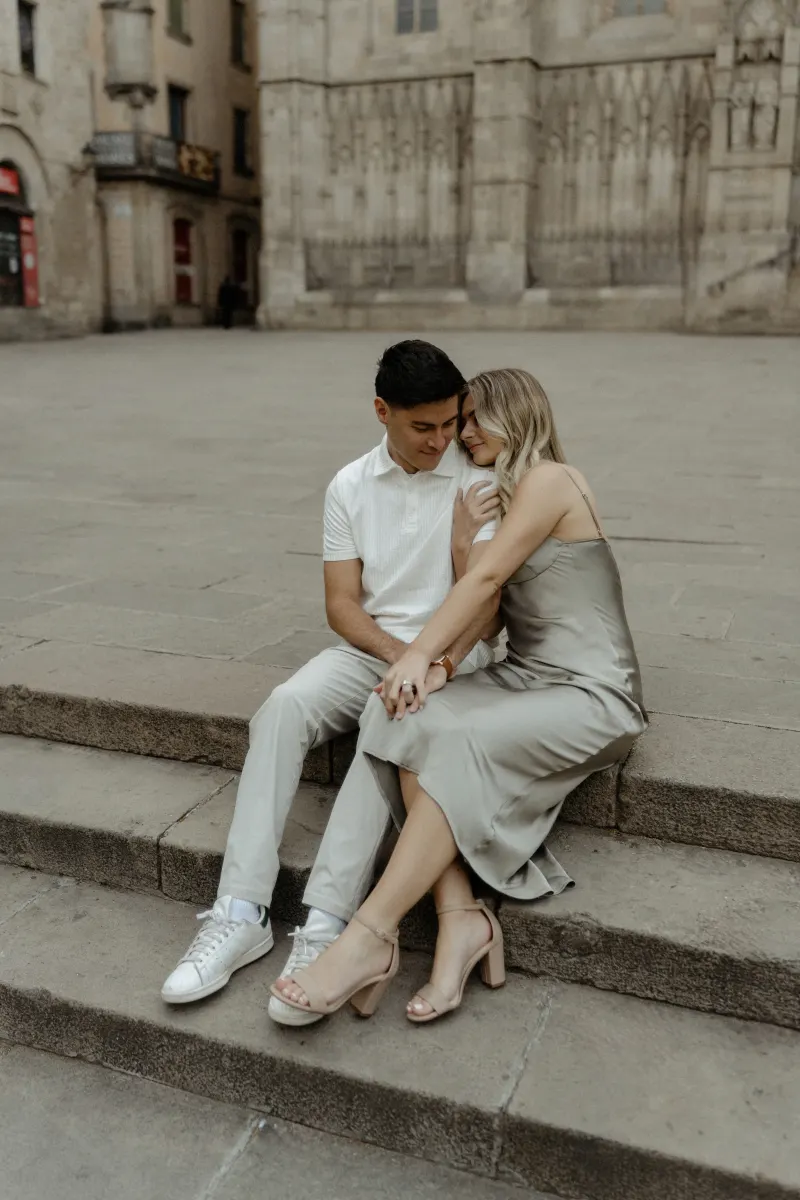 Couple sharing an intimate embrace on historic stone steps in Barcelona during a Vacation Portraits photoshoot.