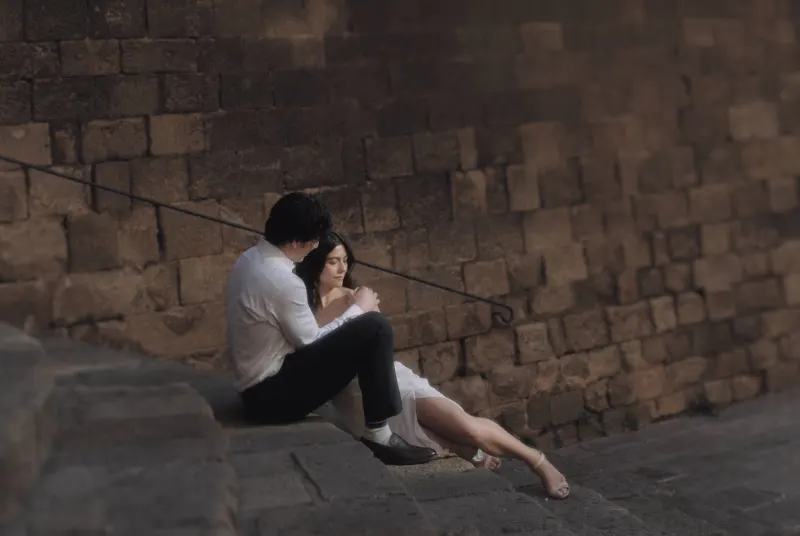 Couple sits close on ancient stone steps, sharing a quiet, intimate moment during a couples & engagements photoshoot.