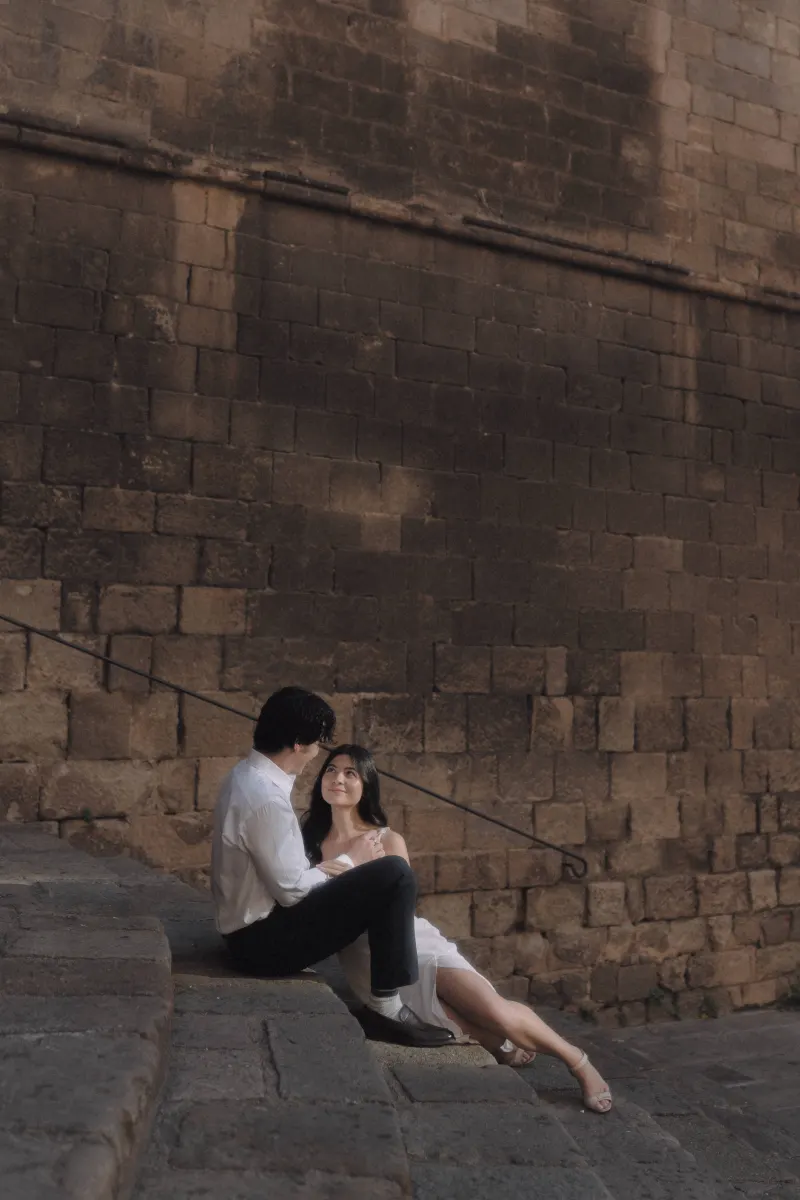 Couple sits close on ancient stone steps, sharing a quiet, loving moment during a couples & engagements photoshoot.