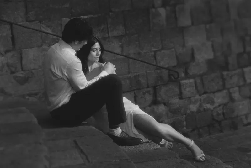 Couple sits close on old stone steps, sharing a quiet, intimate moment during a couples & engagements photoshoot.
