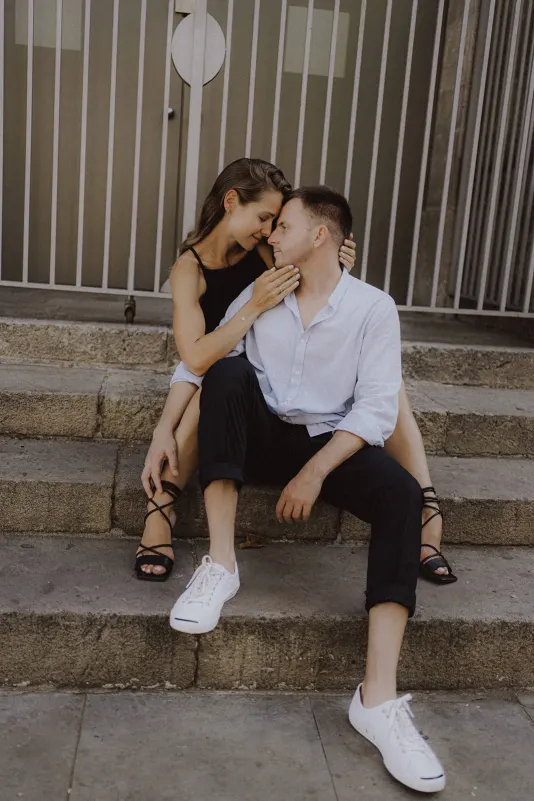 Couple sits close on stone steps, sharing a quiet, affectionate moment during a couples & engagements photoshoot.