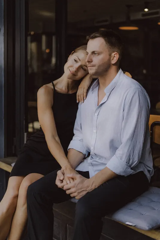 Couple sitting close on a café bench, sharing a quiet, affectionate moment during a couples & engagements photoshoot.
