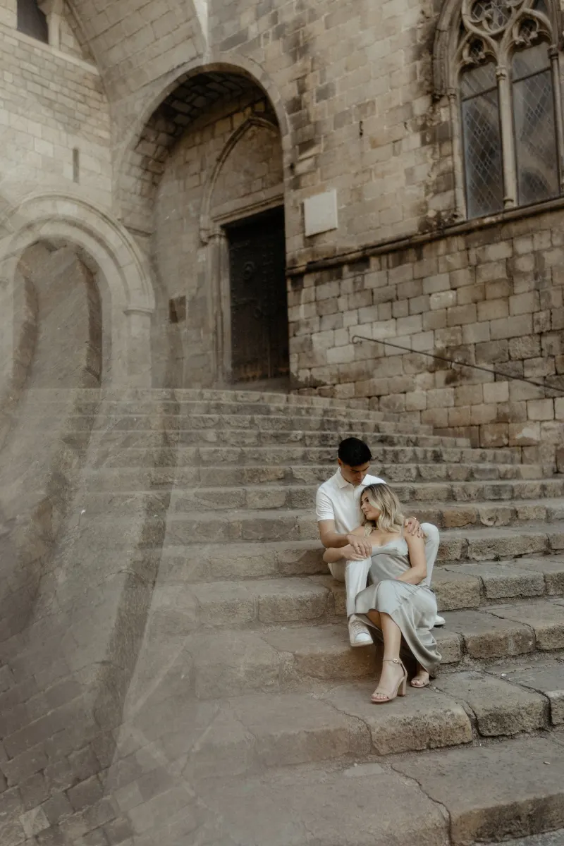 Couple sitting close on ancient stone steps in Barcelona, sharing a peaceful moment during their Vacation Portraits session.