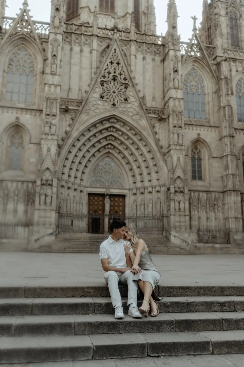 Couple sitting close on cathedral steps in Barcelona, sharing a quiet moment during a Vacation Portraits session.