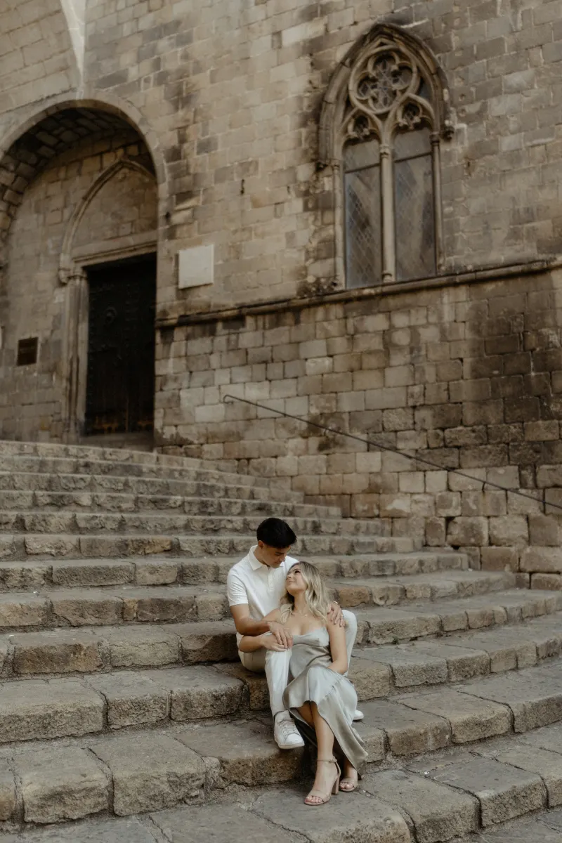 Couple sitting close on historic stone steps in Barcelona, sharing a quiet moment during a Vacation Portraits session.