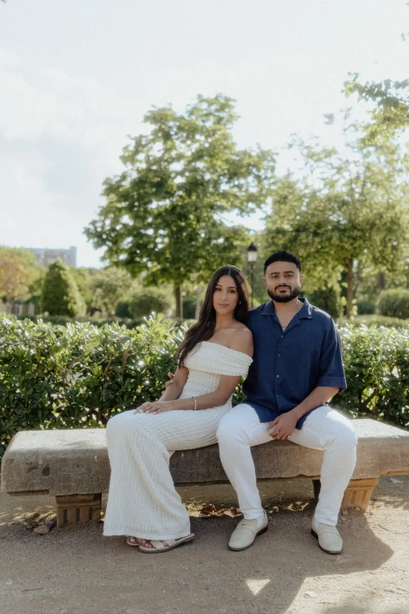 Couple sitting close together on a stone bench, sharing a peaceful moment during an outdoor engagement photoshoot.