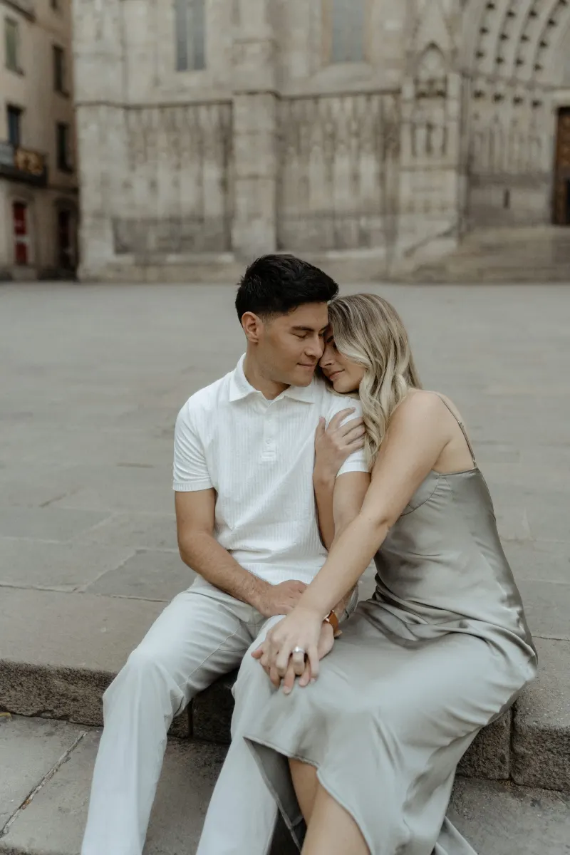 Couple sitting close together on stone steps in Barcelona, sharing a quiet embrace during a Vacation Portraits session.
