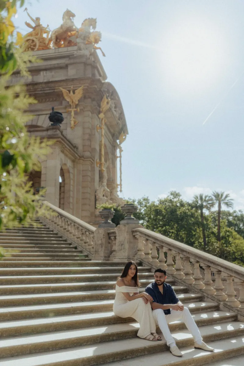 Couple sitting together on sunlit stone steps, sharing a quiet moment during a couples & engagements photoshoot in Barcelona.