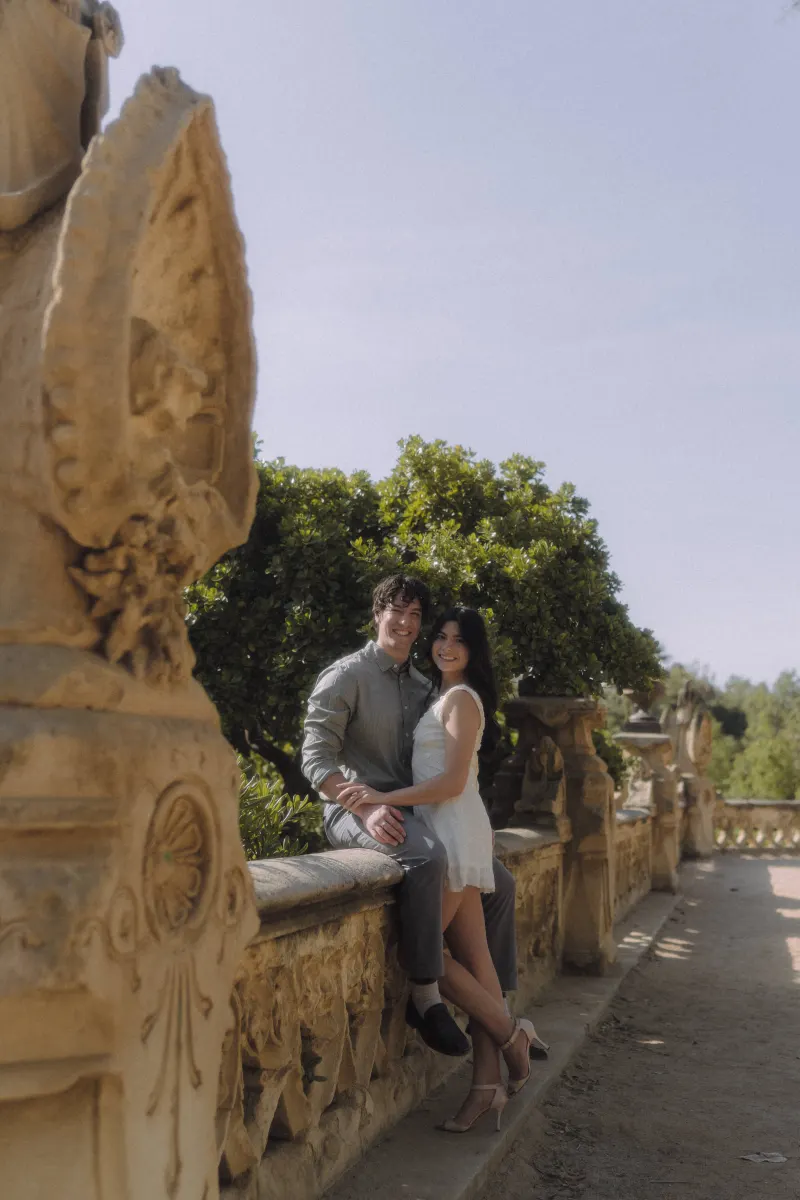 Couple smiling and embracing on a sunlit stone terrace, captured during a romantic couples & engagements photoshoot.