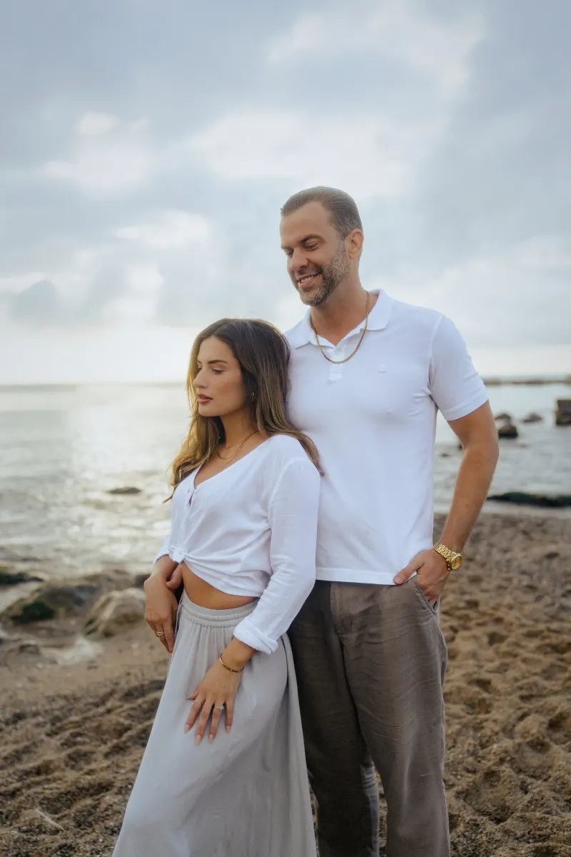 Couple standing together on a serene beach, sharing a peaceful moment during a couples & engagements photoshoot.