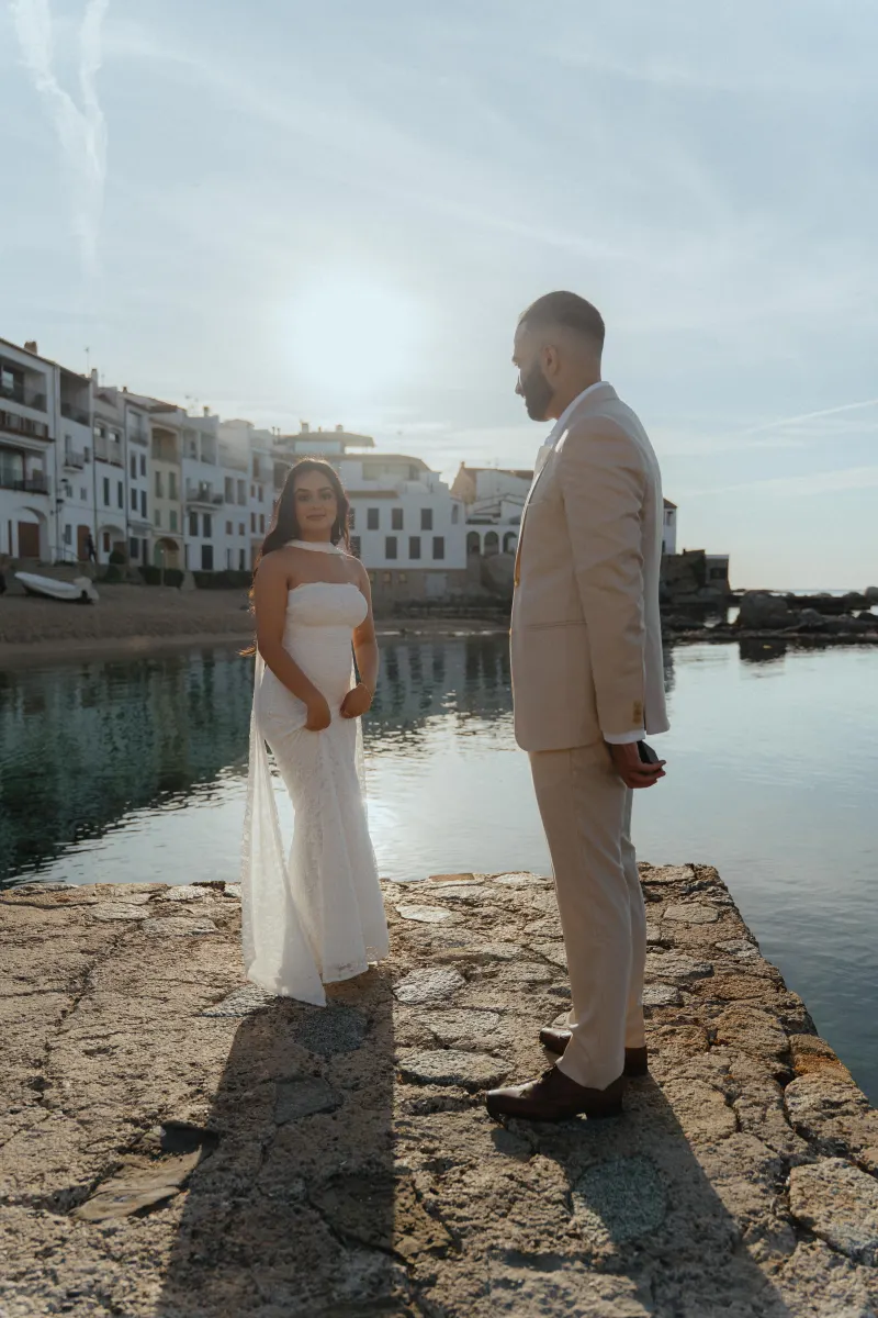 Couple stands by the waterfront at sunset, capturing an emotional surprise proposal photoshoot in a coastal village.