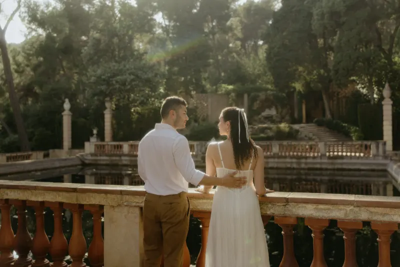 Couple stands close by a tranquil garden pond, sharing a quiet, affectionate moment during their engagement photoshoot.