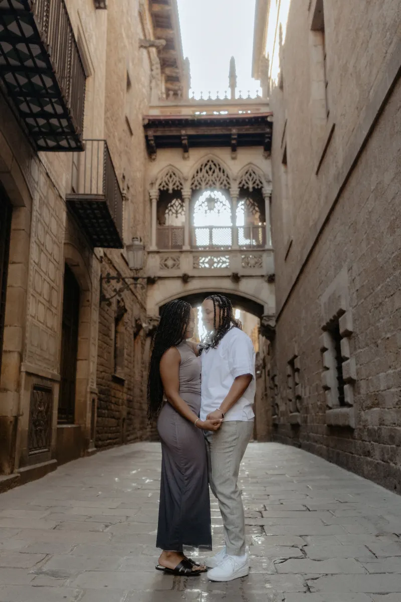 Couple stands close, holding hands and sharing a quiet, emotional moment during a surprise proposal in Barcelona’s Gothic Qua