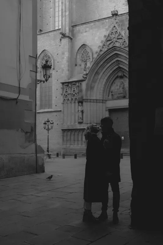 Couple stands close in a quiet Barcelona alley, sharing a romantic moment during an engagement photoshoot.