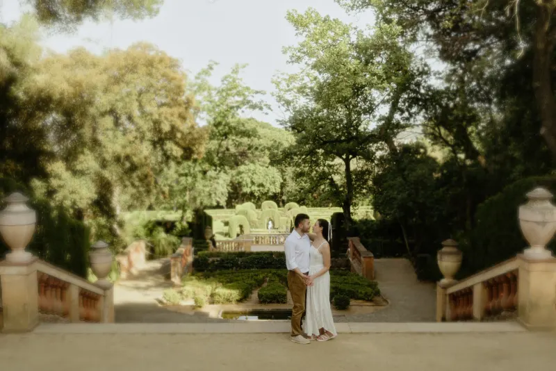Couple stands close on a sunlit garden terrace, sharing a loving gaze during their couples & engagements photoshoot.