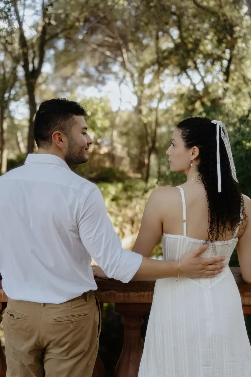 Couple stands close on a wooden terrace, sharing a quiet moment during a couples & engagements photoshoot in the garden.