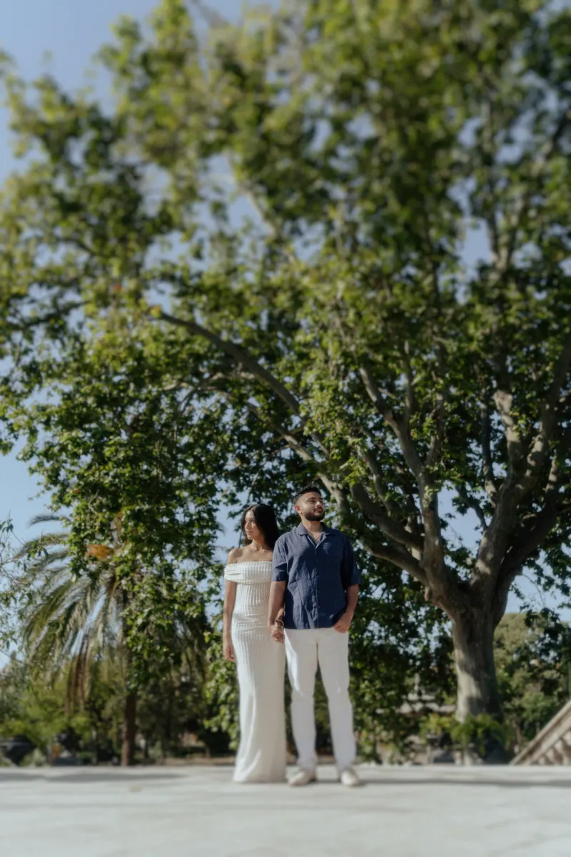 Couple stands together under a large tree, sharing a peaceful moment during an outdoor couples & engagements photoshoot.