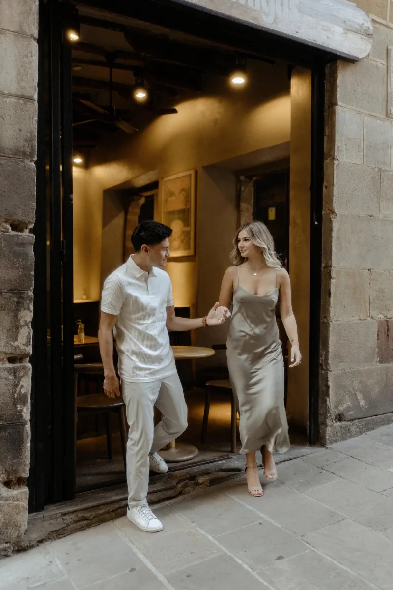 Couple stepping out of a cozy Barcelona café hand in hand, sharing a relaxed moment during a Vacation Portraits session.