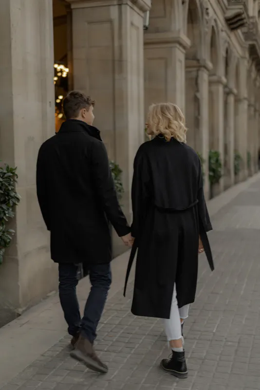 Couple strolls hand in hand beneath stone arches in Barcelona during a couples & engagements photoshoot.