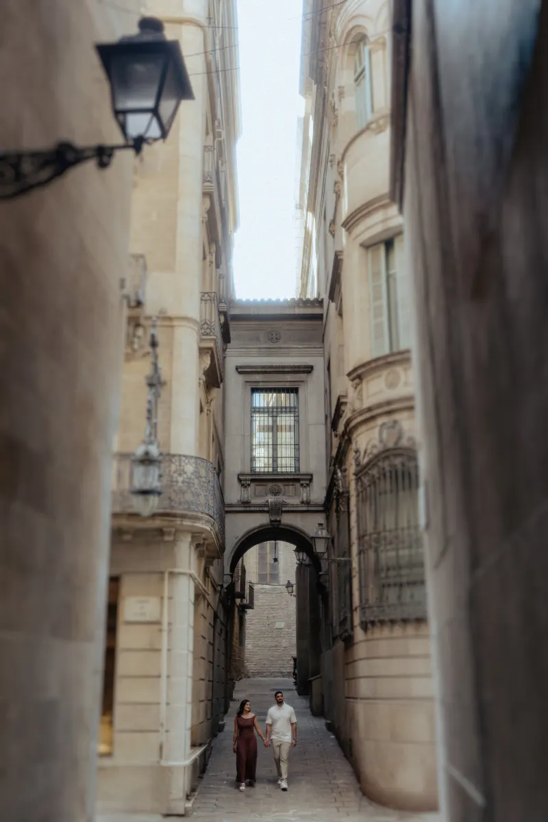 Couple strolls hand in hand through a romantic old city alley during their couples & engagements photoshoot.