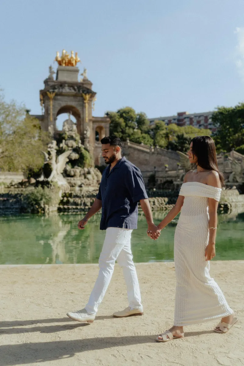 Couple walking hand in hand by a historic fountain, sharing a relaxed moment during a couples & engagements session.