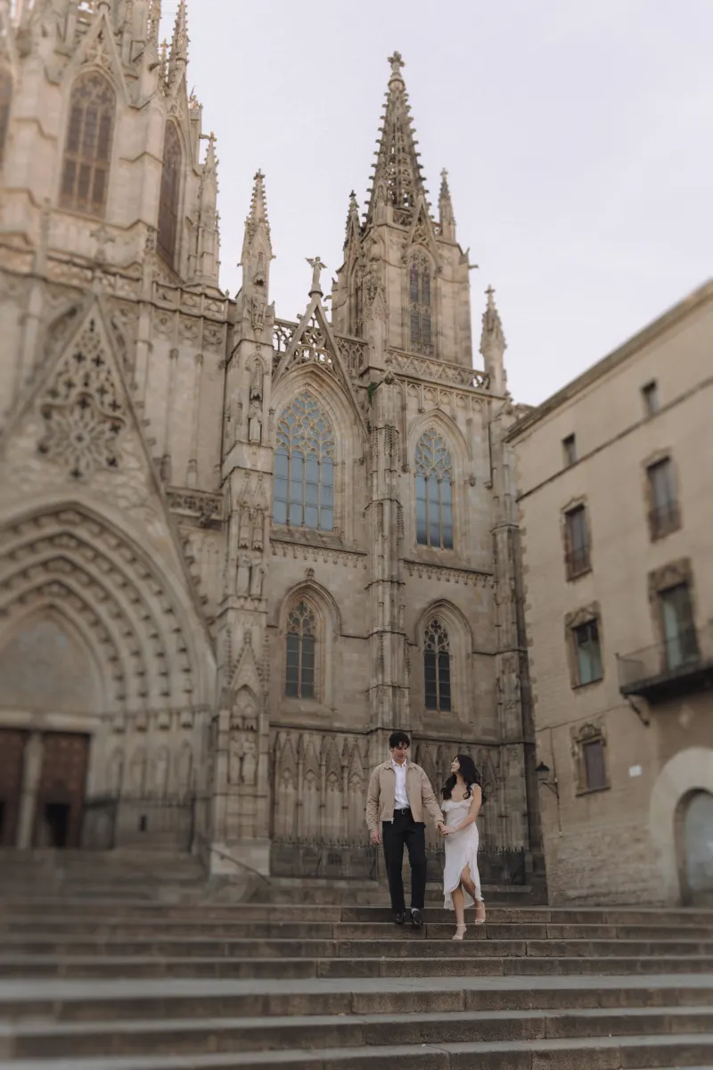 Couple walking hand in hand down cathedral steps, sharing a romantic moment during a couples & engagements photoshoot.