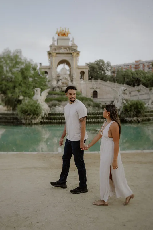 Couple walks hand in hand by the fountain at Parc de la Ciutadella during a relaxed couples & engagements photoshoot.