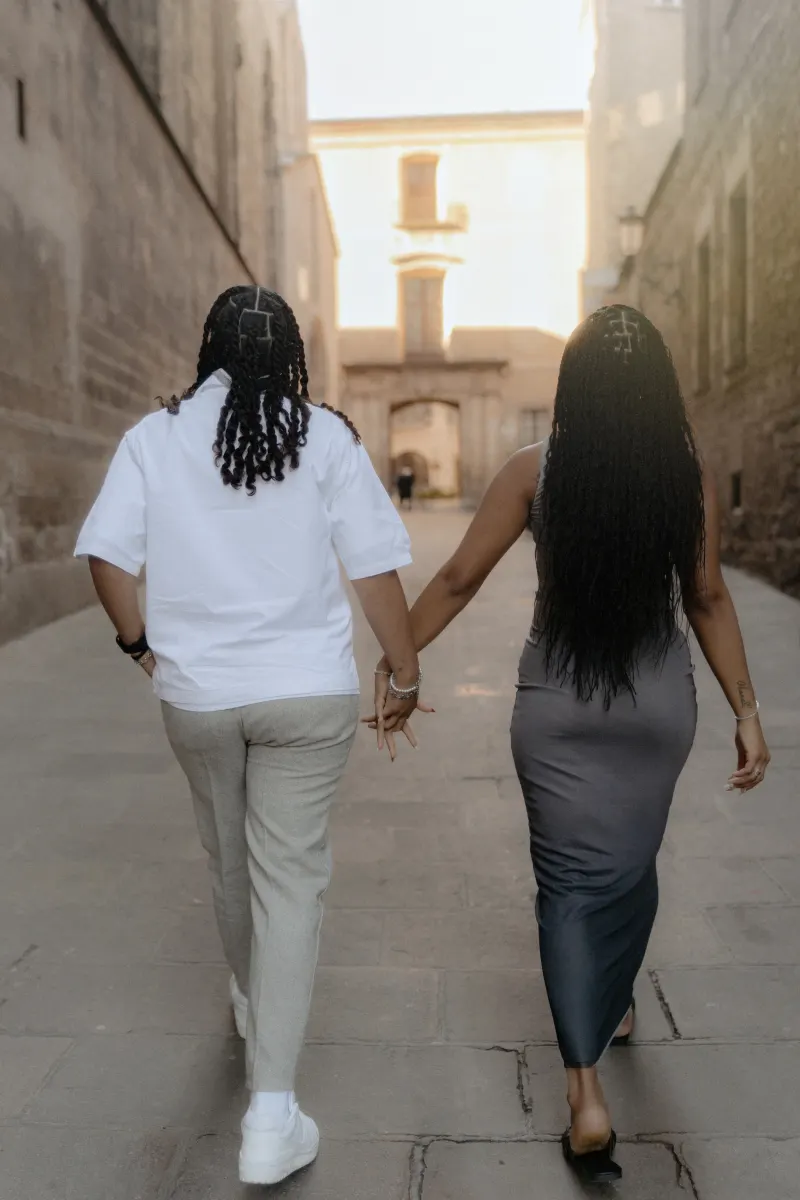 Couple walks hand in hand down a quiet Barcelona street, captured during a surprise proposal photoshoot.