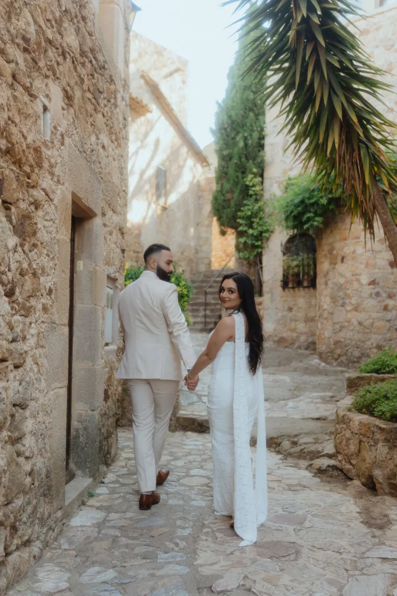 Couple walks hand in hand through a charming stone alley, smiling after their surprise proposal photoshoot.